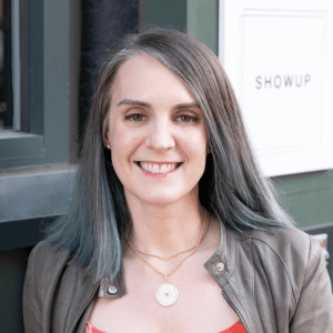 About Thoughts on Art Close-cropped photograph of site author, Christine O'Donnell, standing outside in front of the sign for her nonprofit art gallery, ShowUp